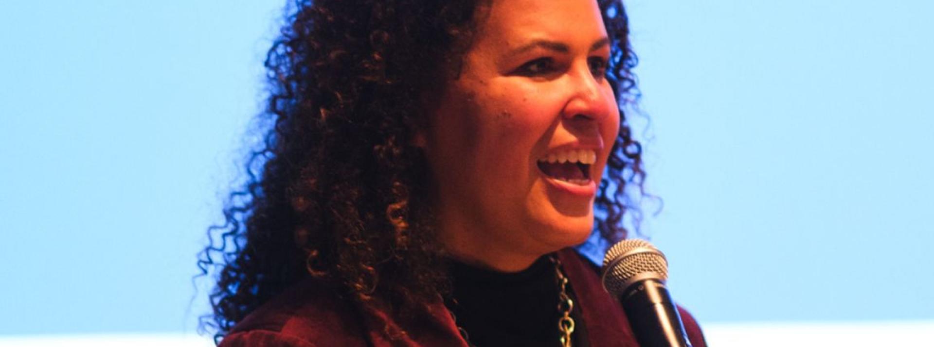 Safiya Noble speaking into and smiling at the microphone