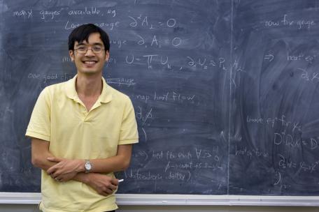 Photo of Terence Tao with a chalkboard behind him