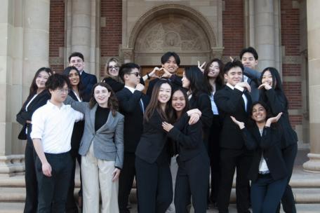 Group of college students dressed professionally posing in front of a brick building.